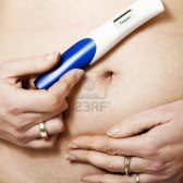 12520746-a-womans-manos-la-celebracion-de-una-prueba-de-embarazo-positiva-en-su-vientre-al-descubierto